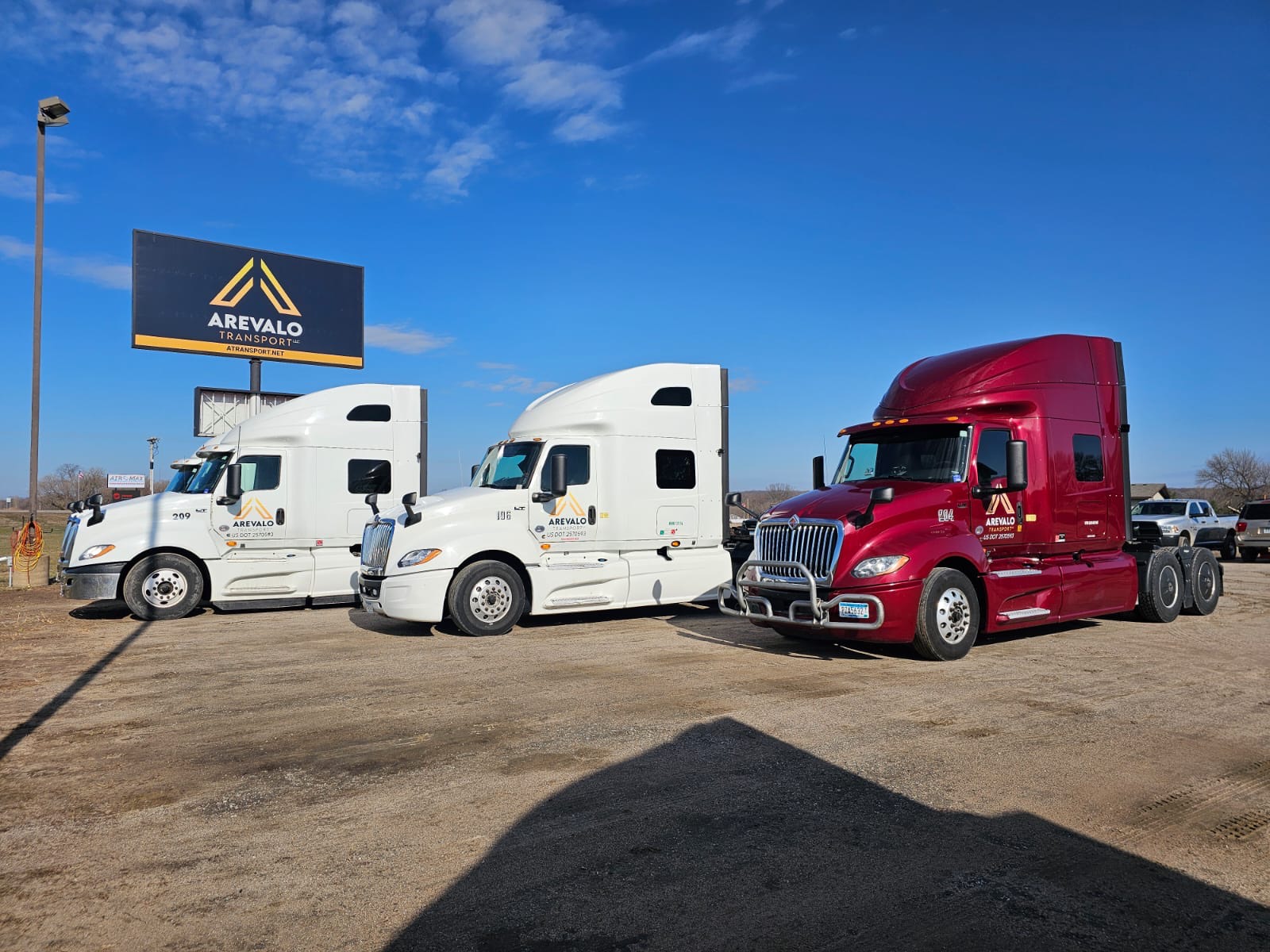 A row of Arevalo Transport trucks under the company sign